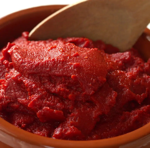 Domates Salçası-1000 Gr. yoğun lezzetli domates salçası bir kapta, ahşap kaşık ile karıştırılıyor.