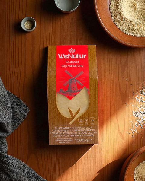 WeNatur Glutensiz Çiğ Nohut Unu 1000 Gr, doğal nohut ununun ambalajı ahşap masa üzerinde.