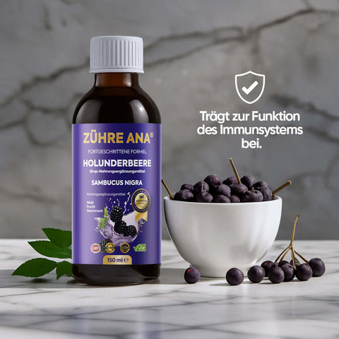 Zühre Ana Kara Mürver Şurubu in a bottle with black elderberries and mint leaves on a wooden surface.