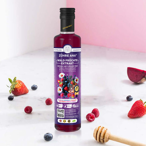 Zühre Ana Orman Meyveleri Özü şişesi, orman meyveleri, doğal bileşenler ve balla birlikte görünmektedir.