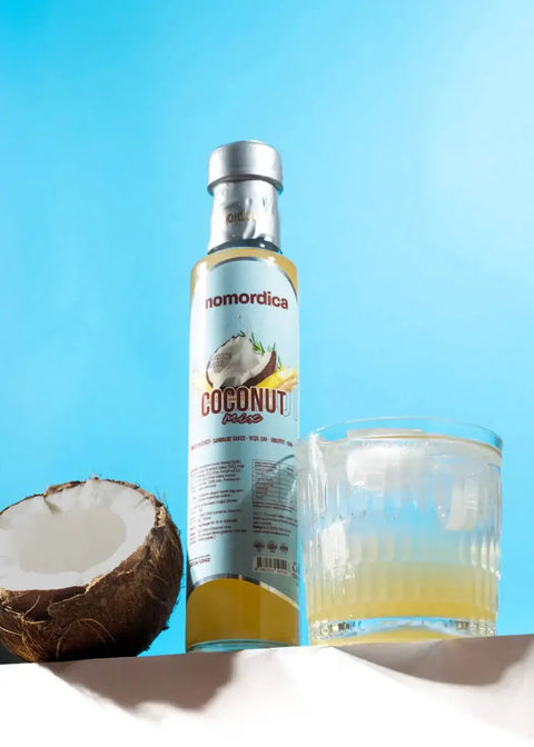Momordica Coconut Mix Hindistan Cevizi Karışımı 250ml şişesi ve bir bardak içecek ile kesilmiş hindistan cevizi.